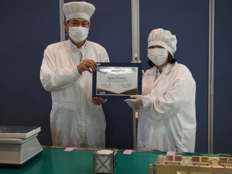 写真2:JAXAへの引き渡しの様子(右側が信川講師)