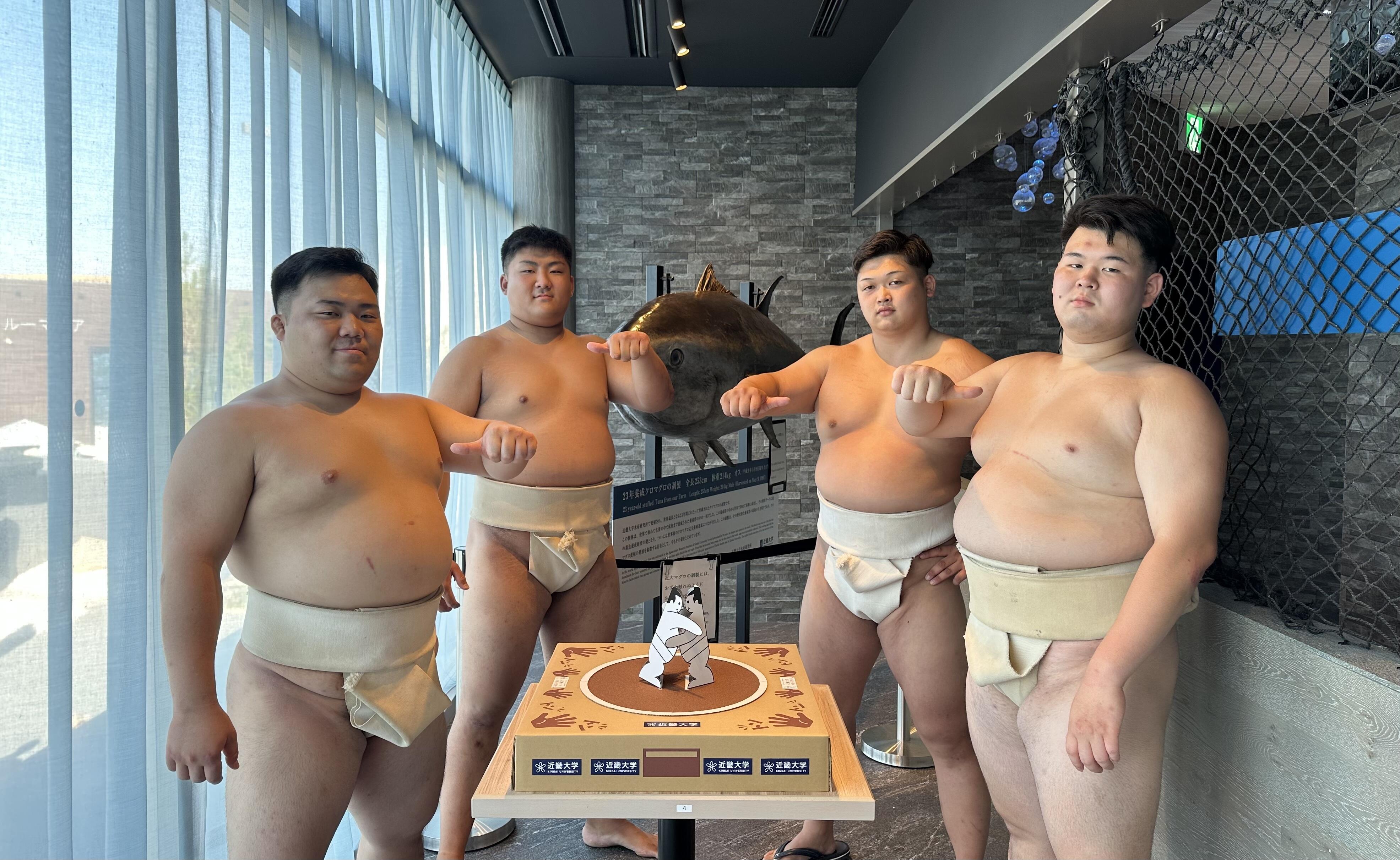 近畿大学体育会相撲部が、近畿大学水産研究所 大阪・関西万博 ウォータープラザ店でお客様と紙相撲対決や写真撮影を実施