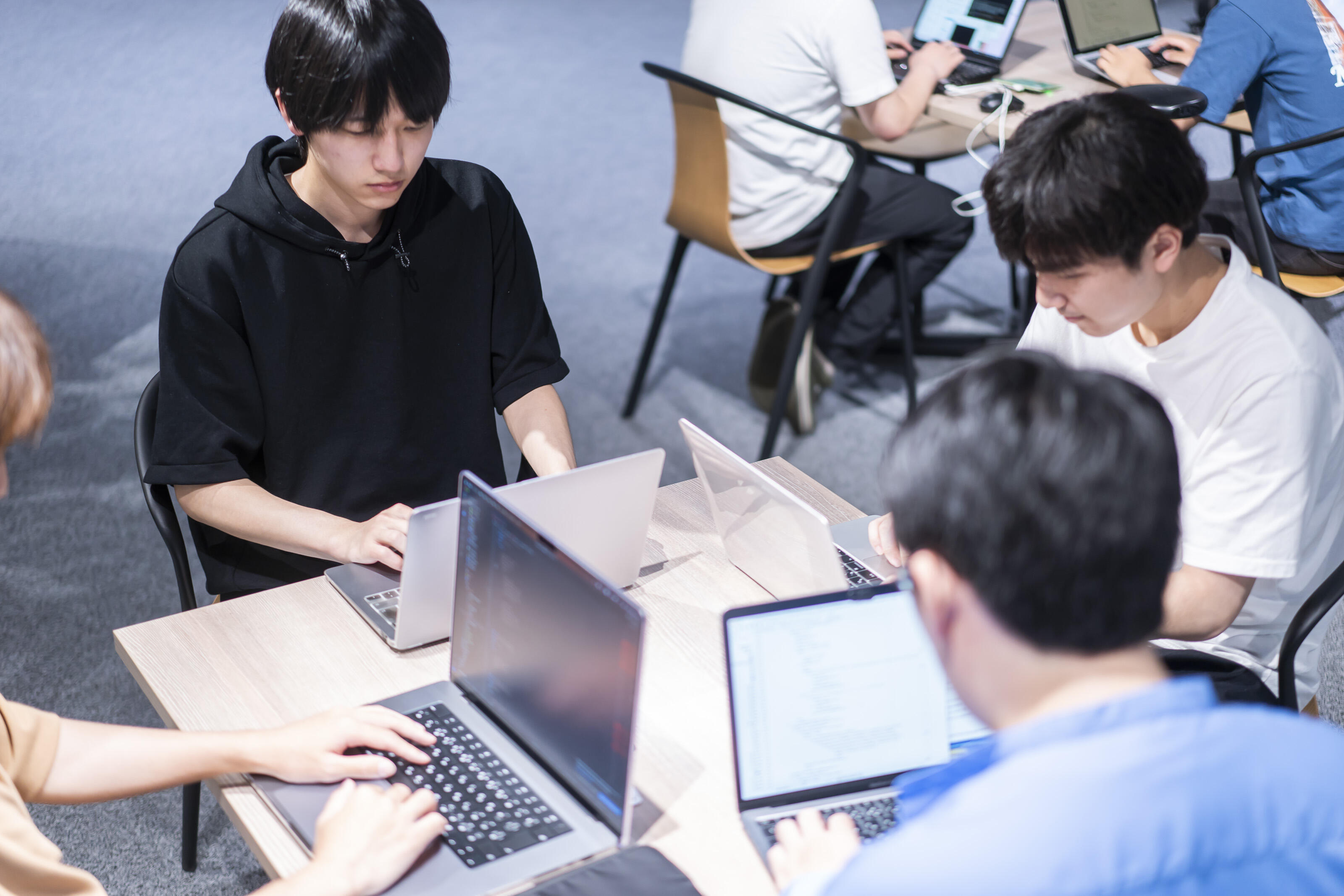 プログラミングBootCampの様子。数人のグループでノートパソコンに向かう学生たち